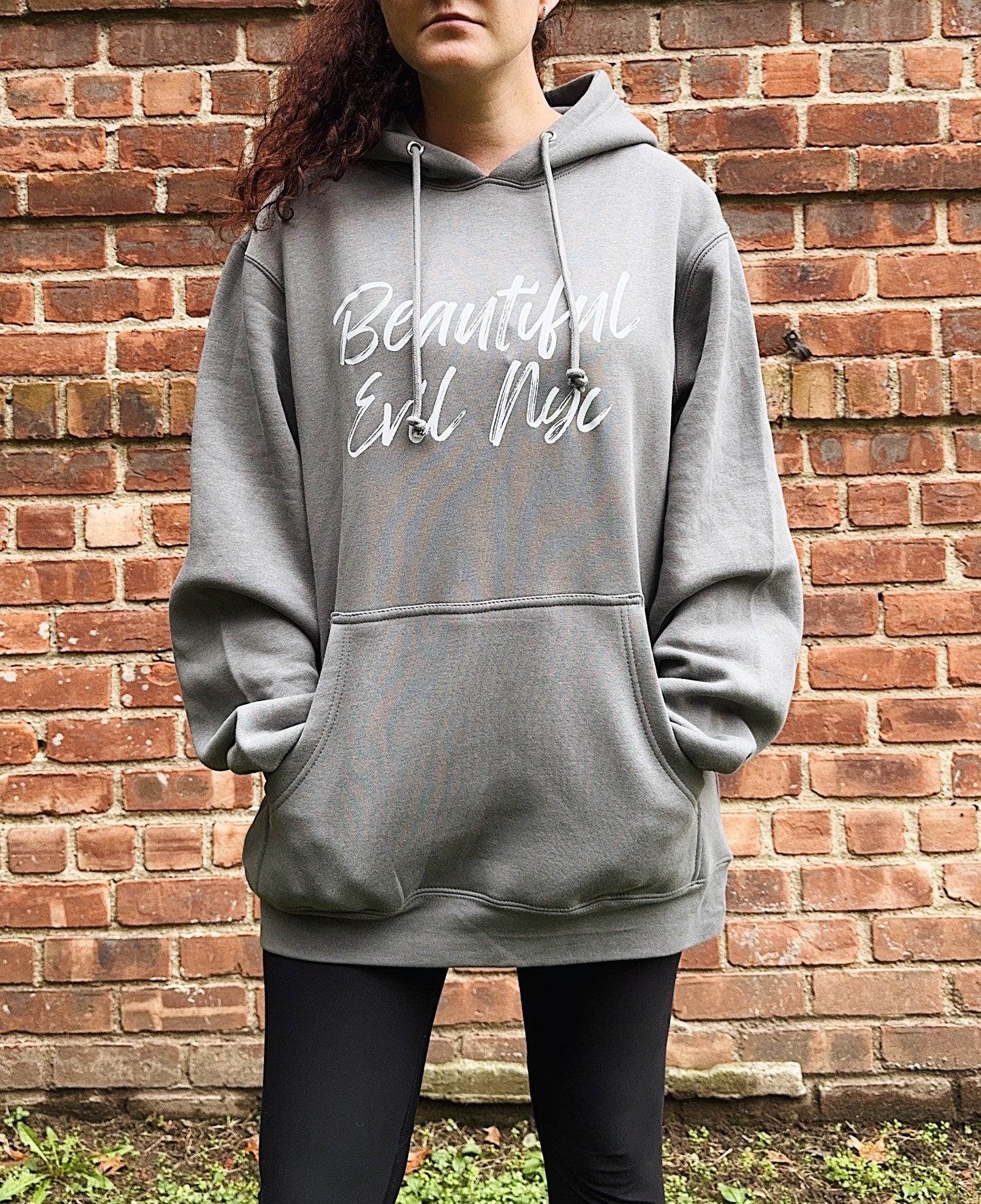 Person wearing a gray hoodie with text against a brick wall