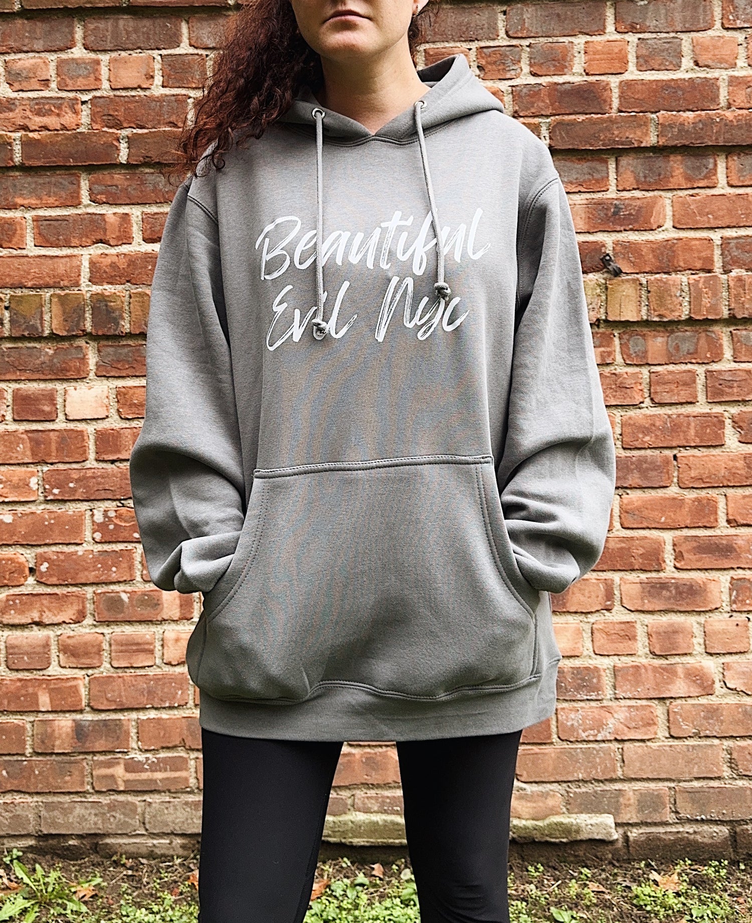 Person wearing a gray hoodie with text against a brick wall