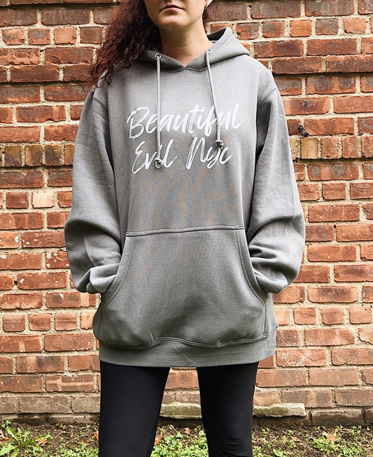 Person wearing a gray hoodie with text against a brick wall